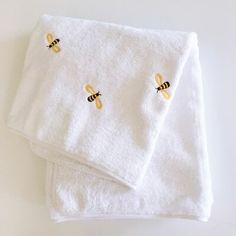 two white towels with yellow bees on them