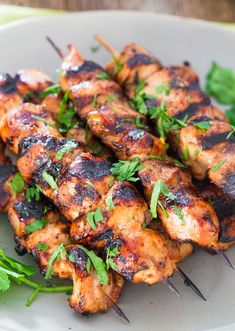 chicken skewers with cilantro and mint garnish on a plate