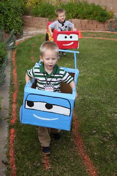 two young boys are playing with cars in the yard