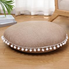 a brown and white pom - pom pillow sitting on top of a wooden floor