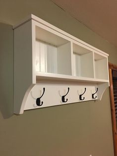 the coat rack has five coats on it and is mounted to the wall with hooks