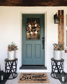 two planters with flowers are sitting on the front steps of a house, next to a blue door