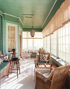 the sun shines through the windows in this green and white room with wicker furniture