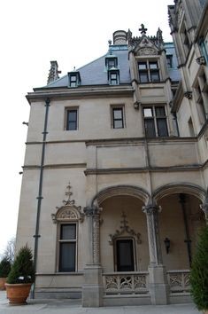 an old building with many windows and ornate decorations on the front door, next to a potted plant