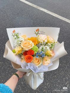 someone is holding a bouquet of flowers on the street