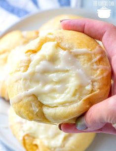 a hand holding a pastry with icing on it