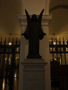 a statue of an angel is in the middle of a room with wrought iron gates