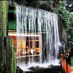 a waterfall with people sitting at tables under it