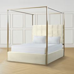 a white bed with a gold frame and pillows on top of it in a room