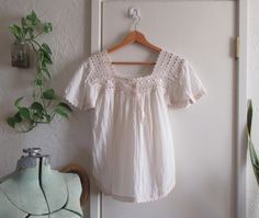 This is a beautiful vintage cotton gauze blouse with lovely ribbon trim and cotton lace embellishments. Semi-sheer cotton gauze in an off-white color, with matching color cotton lace at the neck, sleeves and hem. Round hem, this is a vintage tunic top. Very light pink ribbon drawstring at the neck. No tags. The sleeves have been altered at the tops (see last photo) to make them a bit smaller - this can be reversed if desired. Pleated at the breast under the lace part. Excellent vintage condition! Estimated to be from the 70s. Size approximately S to M, please see measurements. Measurements taken flat in inches: pit to pit 18 waist 22 total length 25 Bohemian Cotton Peasant Top With Lace Trim, Spring Cotton Blouse With Crochet Trim, Cotton Peasant Top With Lace Trim For Daywear, Bohemian Cotton Tops With Lace Trim, Bohemian Cotton Top With Lace Trim, Fitted Cotton Peasant Top In Cottagecore Style, Fitted Cotton Peasant Top Cottagecore Style, Summer Cotton Blouse With Crochet Trim, White Cotton Cottagecore Peasant Top