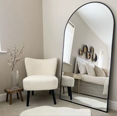 a mirror sitting in the middle of a living room next to a chair and ottoman