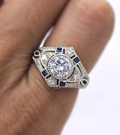 a person's hand holding a diamond and blue sapphire ring