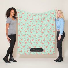 two women standing next to each other holding up a flamingo print blanket with the name madison on it