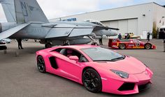 a pink sports car parked in front of an airplane