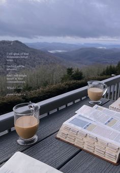 an open book and two cups of coffee on a deck