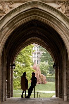 two people standing under an archway in a building