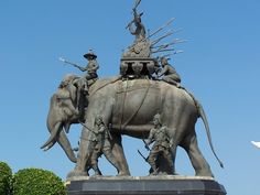 an elephant statue with people riding on it's back in front of a blue sky