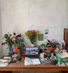 a wooden table topped with lots of plants and books next to a laptop computer on top of a wooden desk