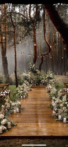 an outdoor ceremony setup with flowers and candles on the ground, surrounded by trees in the background