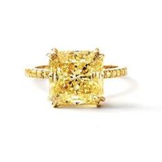 a fancy yellow diamond ring set in 18k gold with diamonds on the band and shoulders