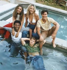 a group of people are posing in the water near a swimming pool with their arms around each other