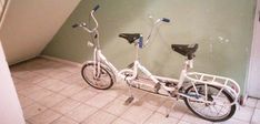 two bikes parked next to each other in a room with tile flooring and green walls