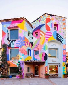 a multicolored building with an artistic mural on it's front and side