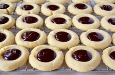 cookies with chocolate fillings on a cooling rack ready to be baked in the oven