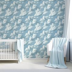 a baby's room with clouds on the wall and crib next to it