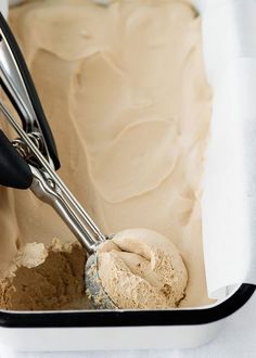 a scoop of ice cream in a white container with tongs sticking out of it