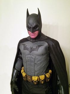 a man in a batman costume standing next to a wall