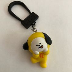 a yellow and black key chain with a cartoon character on it's face, hanging from a hook