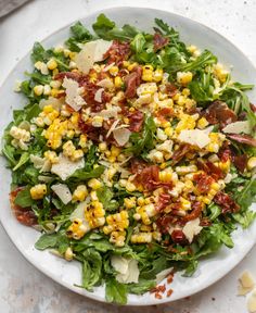 a white bowl filled with salad and topped with bacon, cheese and lettuce