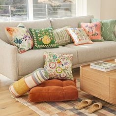 a living room filled with lots of pillows on top of a wooden table next to a couch