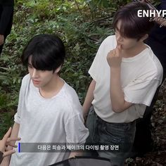 two young men standing next to each other in front of some trees and bushes,