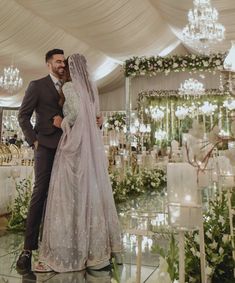 a bride and groom pose for a photo in front of their wedding ceremony setup with chandeliers