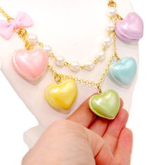 A cute and sweet statement necklace for Valentine's Day or lovecore season! This kawaii charm necklace includes Five heart shaped macaron ( macaroon ) pendants in pastel shades with a pearly finish and whipped cream center. Each necklace includes five 1" (2.5 cm) size charms hanging on a two-layered chain necklace with glass pearls on your choice of a 21" gold plated or silver plated chain. Accented with a baby pink fabric ribbon bow on one side. Necklace will be finished with a Fatally Feminine Multicolor Heart-shaped Kawaii Jewelry, Kawaii Multicolor Heart-shaped Jewelry, Kawaii Necklaces For Valentine's Day, Cute Pastel Jewelry For Gifts, Cute Pastel Jewelry For Gift, Kawaii Style Necklaces For Valentine's Day Gift, Cute Multicolor Heart Charm Necklace, Pastel Kawaii Jewelry Perfect For Gifts, Kawaii Pastel Jewelry For Gifts