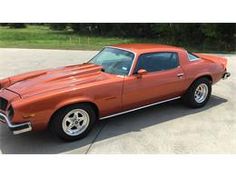 an orange muscle car parked in a parking lot