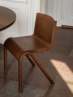 a wooden chair sitting next to a table on top of a tile floor in front of a white door