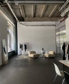 an empty room with chairs and clothes on hangers