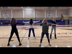 four girls are standing in a gym with their arms stretched out and one girl is holding her hands out