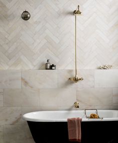 a bath tub sitting next to a shower head in a bathroom with white and black tile