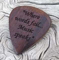 a wooden guitar pick that says where words fail music speaks