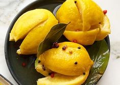 a black plate topped with sliced lemons and pomegranate on top of a table