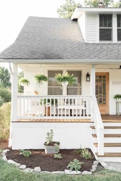 a white house with plants on the front porch