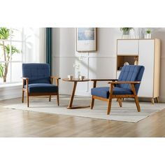 two chairs and a table in a room with hardwood floors, white walls and blue upholstered furniture