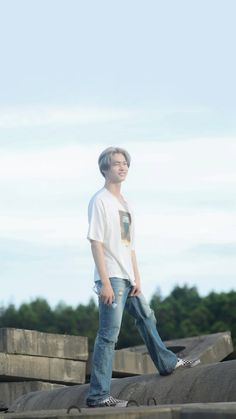 a young man standing on top of a pile of cement blocks with his hands in his pockets