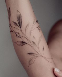 a woman's arm with a branch tattoo on it