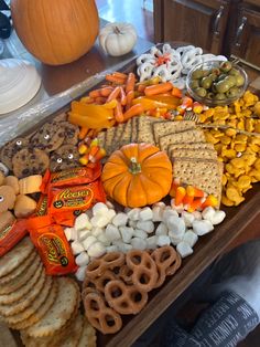 an assortment of snacks are arranged on a table with pumpkins and other food items