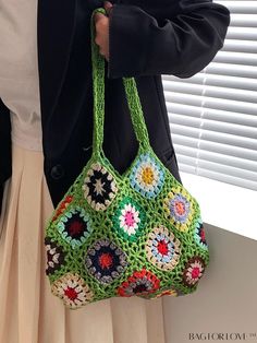 a woman is holding a crocheted bag in her hands and wearing a black jacket